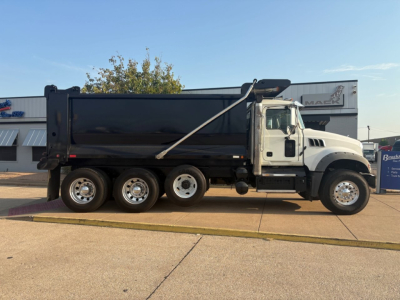 Dump truck side view showing a white 2021 Mack GR64F with black dump body, six-wride rear, chrome wheels, and VIN visible in listing.