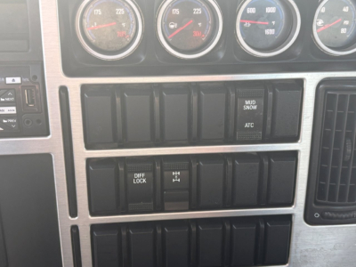 Dashboard area of a 2021 Mack GR64F showing multiple gauges and row of switch panels with labels like DIFF LOCK and H R1. ATC and MUD/ SNOW indicators visible.