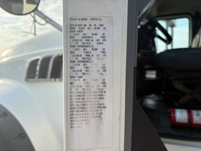 Vehicle information sticker on the door jamb of a Mack truck showing specs and numbers in small print.