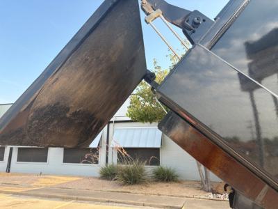 Dump truck bed showing hydraulic dump mechanism and metal side paneling with wear marks.