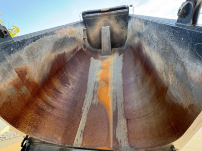 Dump truck bed interior showing metal wear marks and scuff lines along the curved sides.