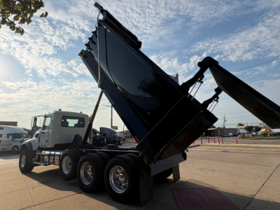 Dump truck rear dump bed raised on a Mack GR64F truck showing hydraulic system and rear wheels.