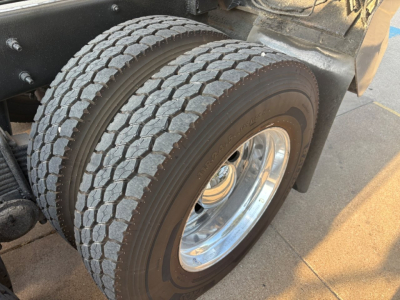 Mack GR64F dump truck rear dual wheels showing tire tread and chrome wheel with fender and undercarriage components.