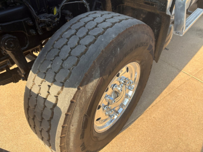 Mack heavy truck front wheel and tire showing chrome hub and tire tread detail.