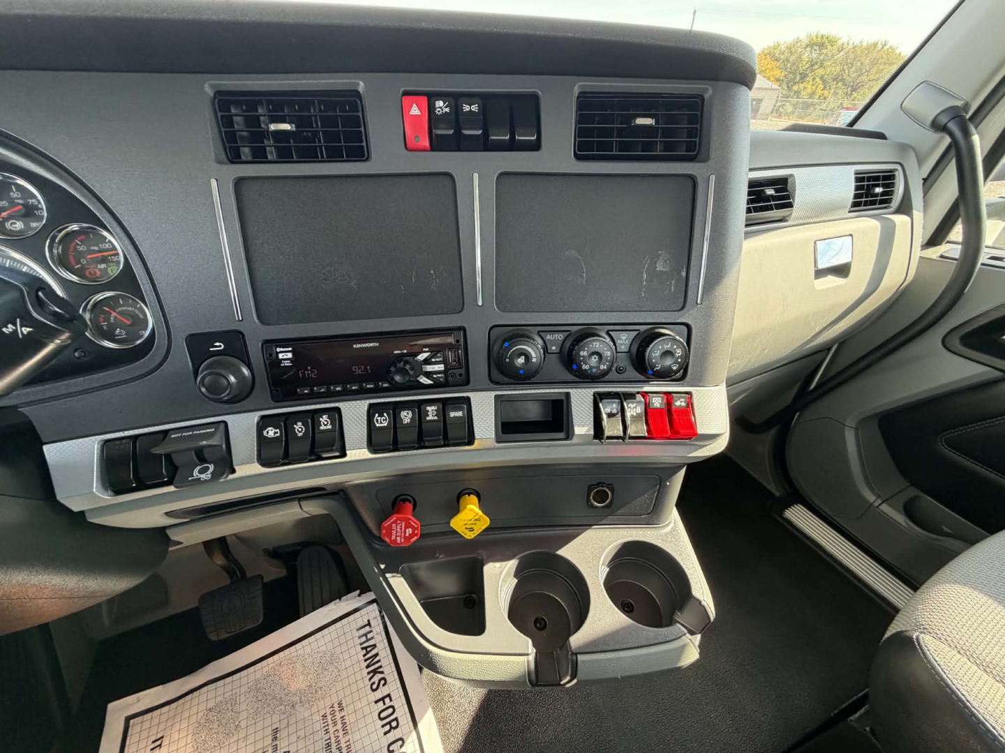 Kenworth T880 cab interior showing dashboard controls, vents, switches, and cup holders.