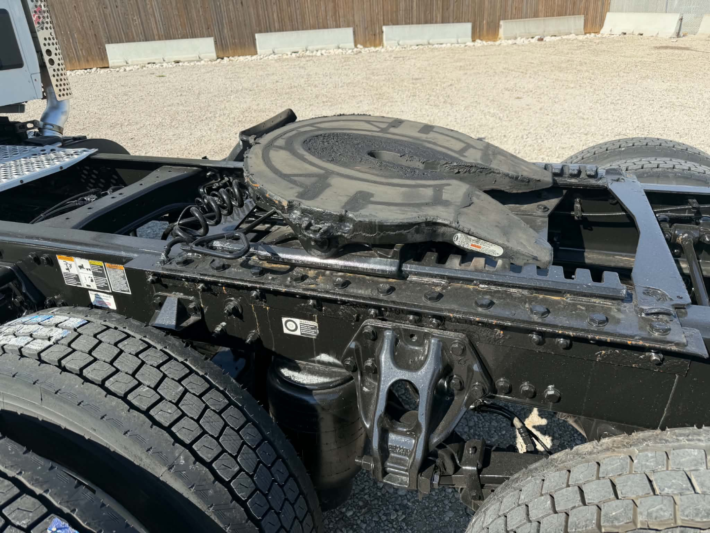 Truck chassis frame with fifth wheel and spare wheel mounting on Kenworth T880, visible labels and components along frame.