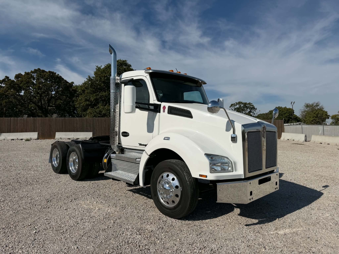 Kenworth T880 daycab truck in white, side view showing front grille, large mirrors, dual rear axles, and tall exhaust stack.