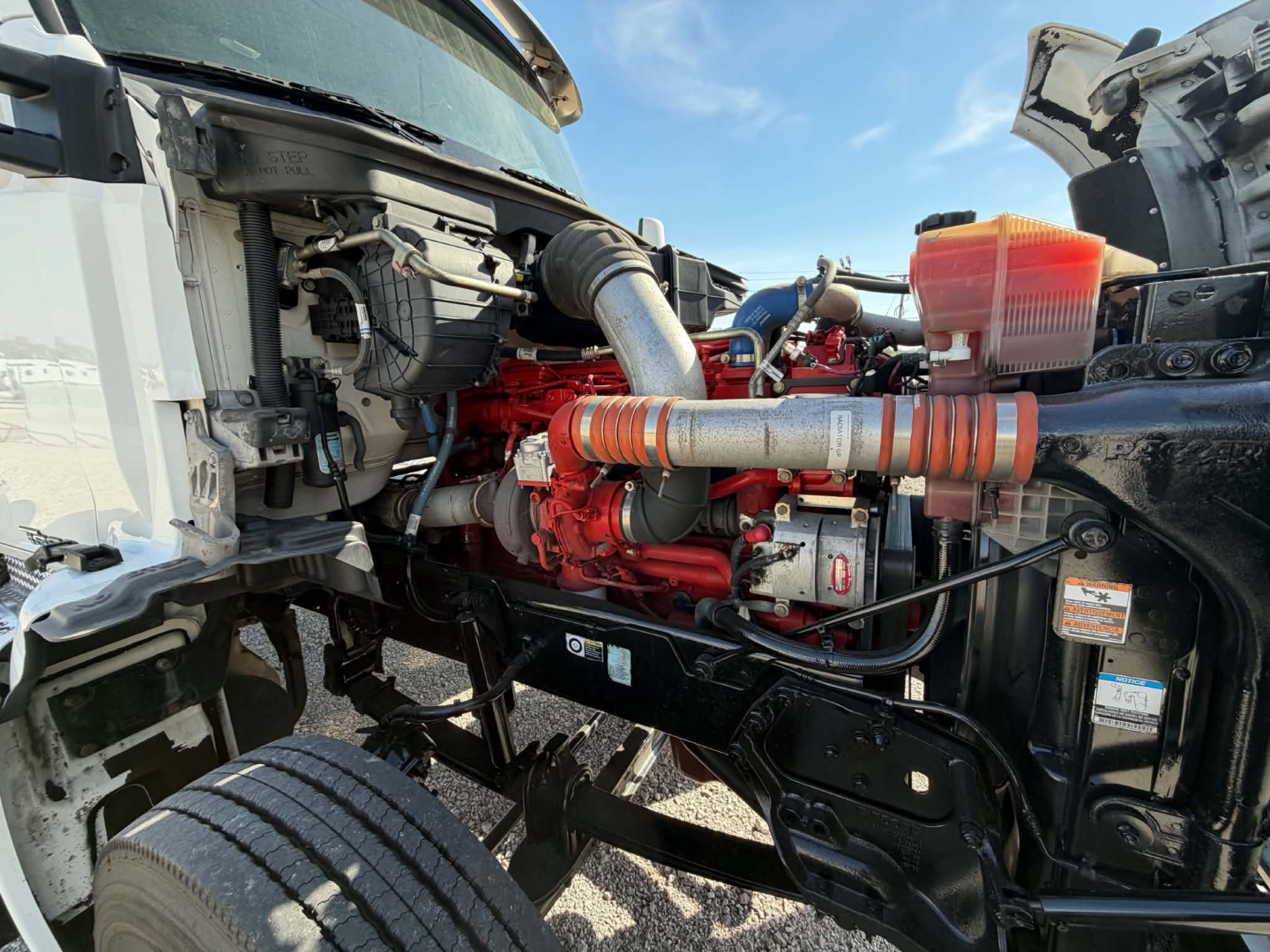 Kenworth T880 engine bay showing red diesel engine, intake hoses, and surrounding components.