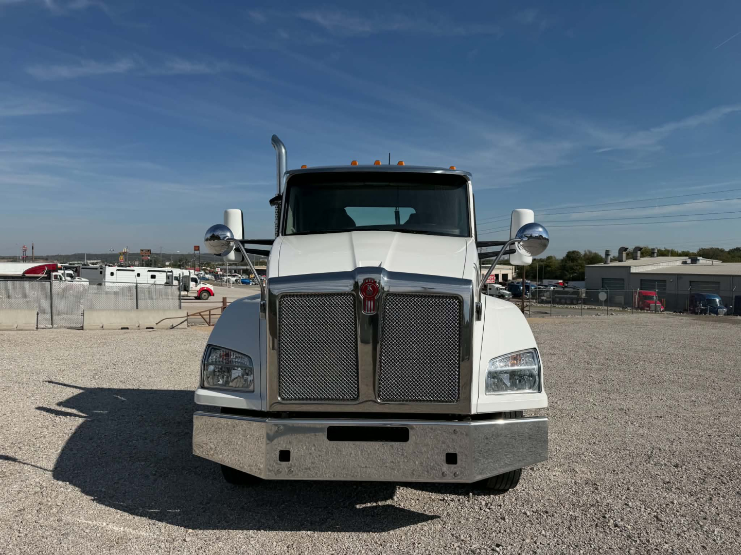 Kenworth T880 conventional daycab truck front view showing chrome grille, bumper, and large rectangular headlights.