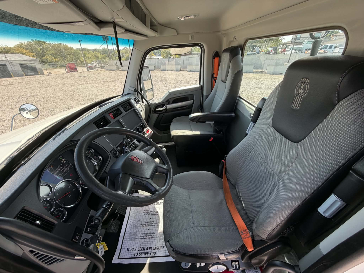 Kenworth T880 interior view showing steering wheel, dashboard, and driver seat with seat belt.