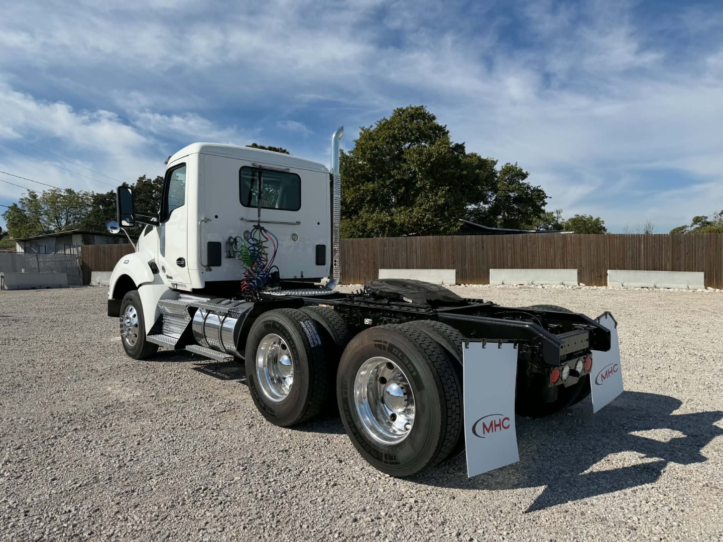 Kenworth T880 tractor cab at rear angle showing chassis and dual rear axles with chrome wheels and MHC mud flaps.
