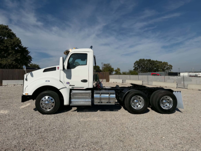 Kenworth T880 conventional daycab truck in white, side view. Crew cab with large fuel tanks and dual rear axles. No visible license plate.