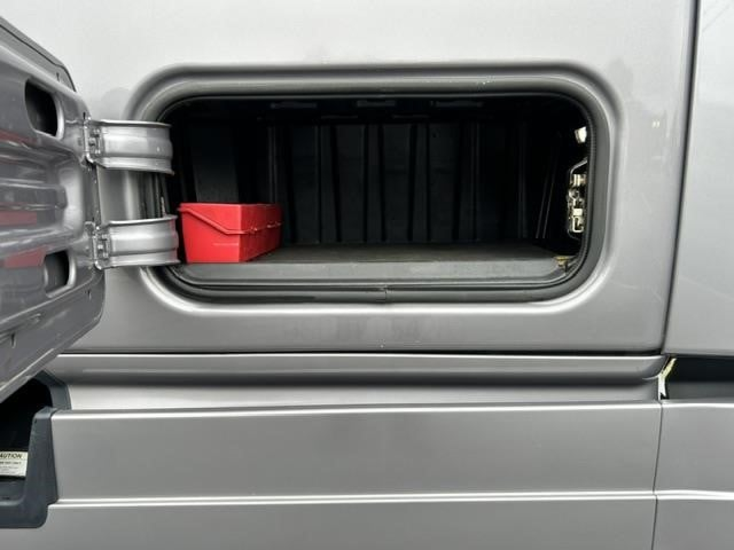 Freightliner Cascadia 126 fuel/air tank area showing storage bay with red toolbox inside side compartment.