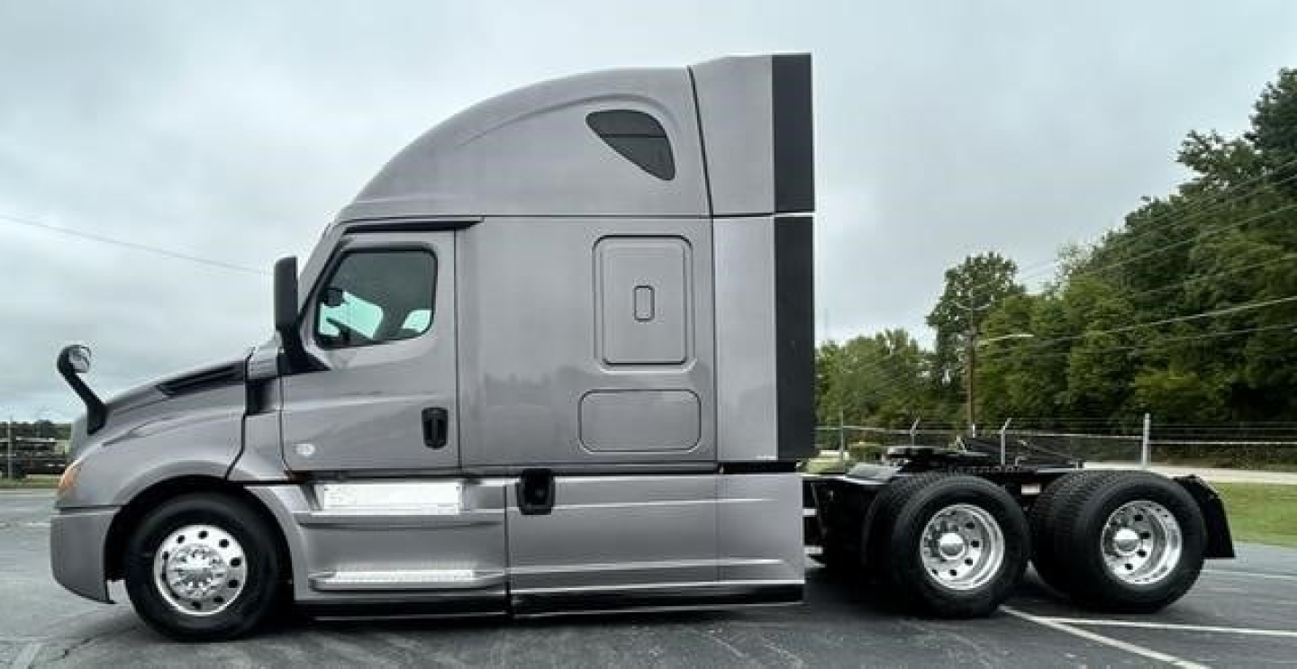 Truck side view showing Freightliner Cascadia 126 sleeper cabin and 6-wheel rear axle with chrome steps and fuel tanks.