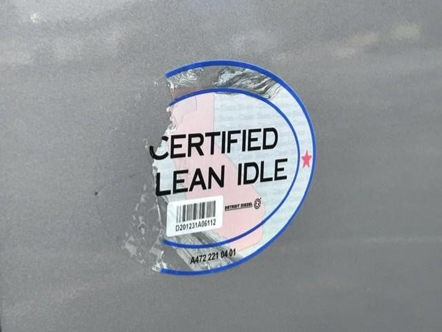 Sticker on Freightliner Cascadia showing certified clean idle seal with barcode and circular logo