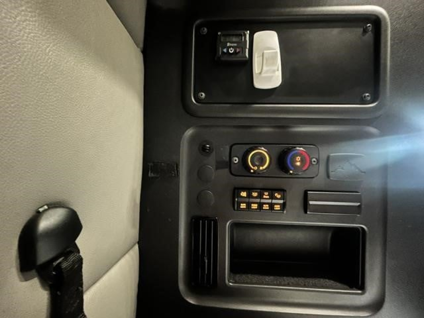 Dashboard area of a Freightliner Cascadia interior showing a small panel with a USB-like plug, climate controls, and open storage pocket.