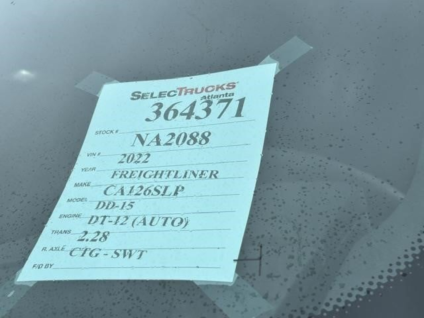 Truck tag on windshield showing stock number 364371, VIN NA2088, year 2022 Freightliner CA126SLP model, engine DT-12 (AUTO), transmission 2.28, gear? XCT-SWT.