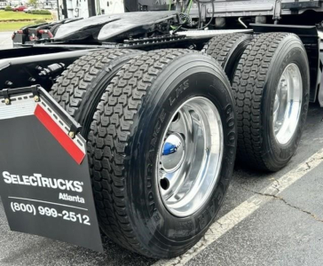 Freightliner Cascadia 126 rear dual-axle wheels and tires visible with chrome rims and mudflap showing SelectTrucks Atlanta contact number