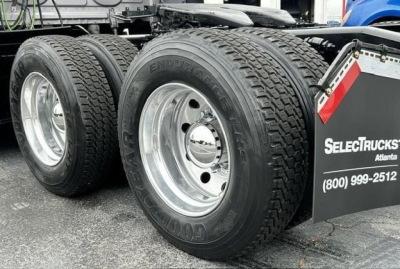 Conventional sleeper truck rear wheels and dual tires showing Endurance Goodyear tires and polished rims; part of Freightliner Cascadia chassis with a SelectTrucks sign on rear.