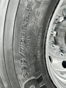 Tire sidewall details on Freightliner Cascadia wheel showing tire size 295/75R22.5 and load rating; wheel hub and rim visible