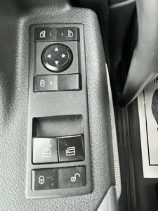 Controls panel with window/mirror adjustment buttons and lock switches inside a Freightliner Cascadia truck cab window control cluster.