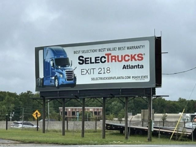 Billboard advertising Select Trucks Atlanta dealership for freight trucks, blue truck graphic, Exit 218 text.