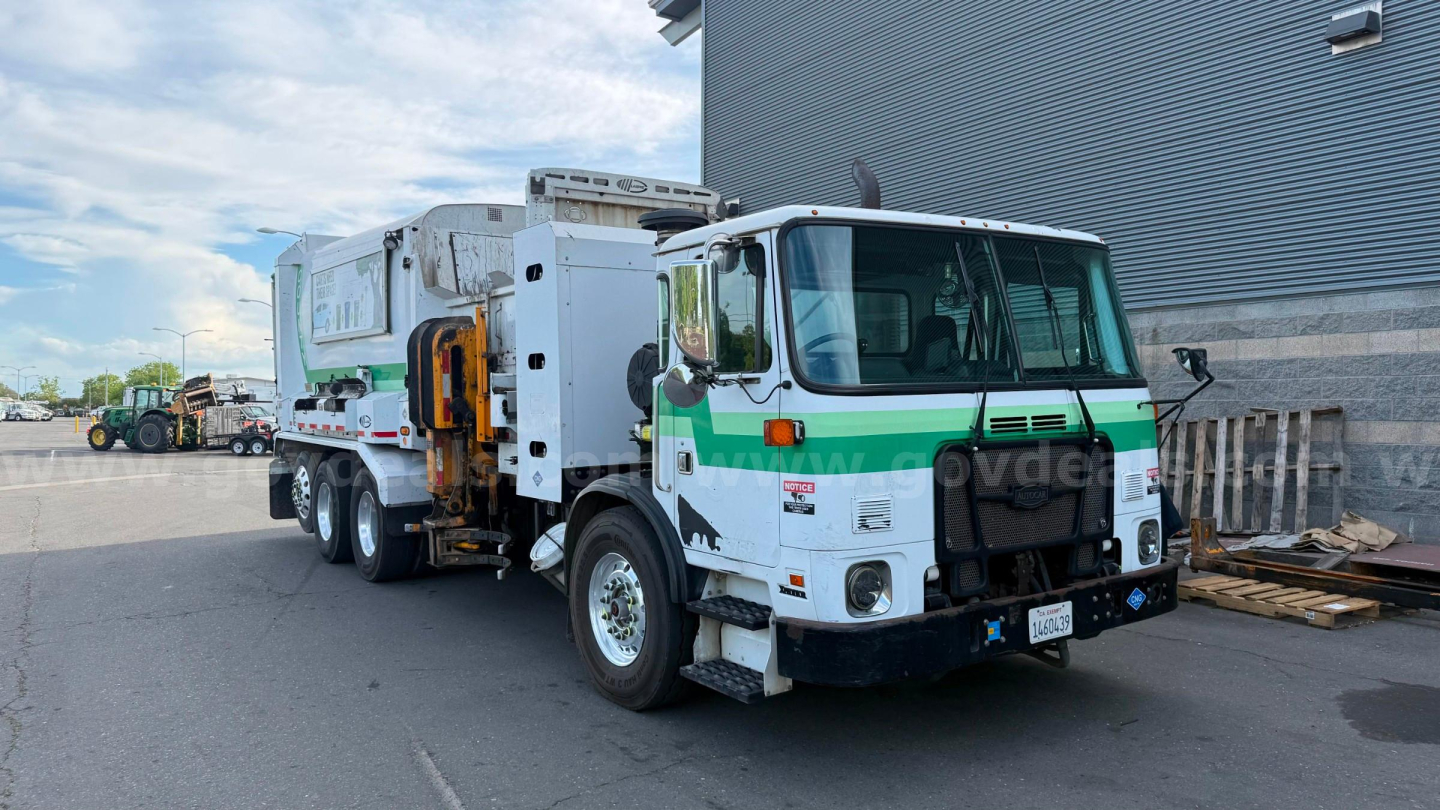 Autocar ACX Xpeditor garbage truck in service standing front-right view with green stripe and rear compactor unit
