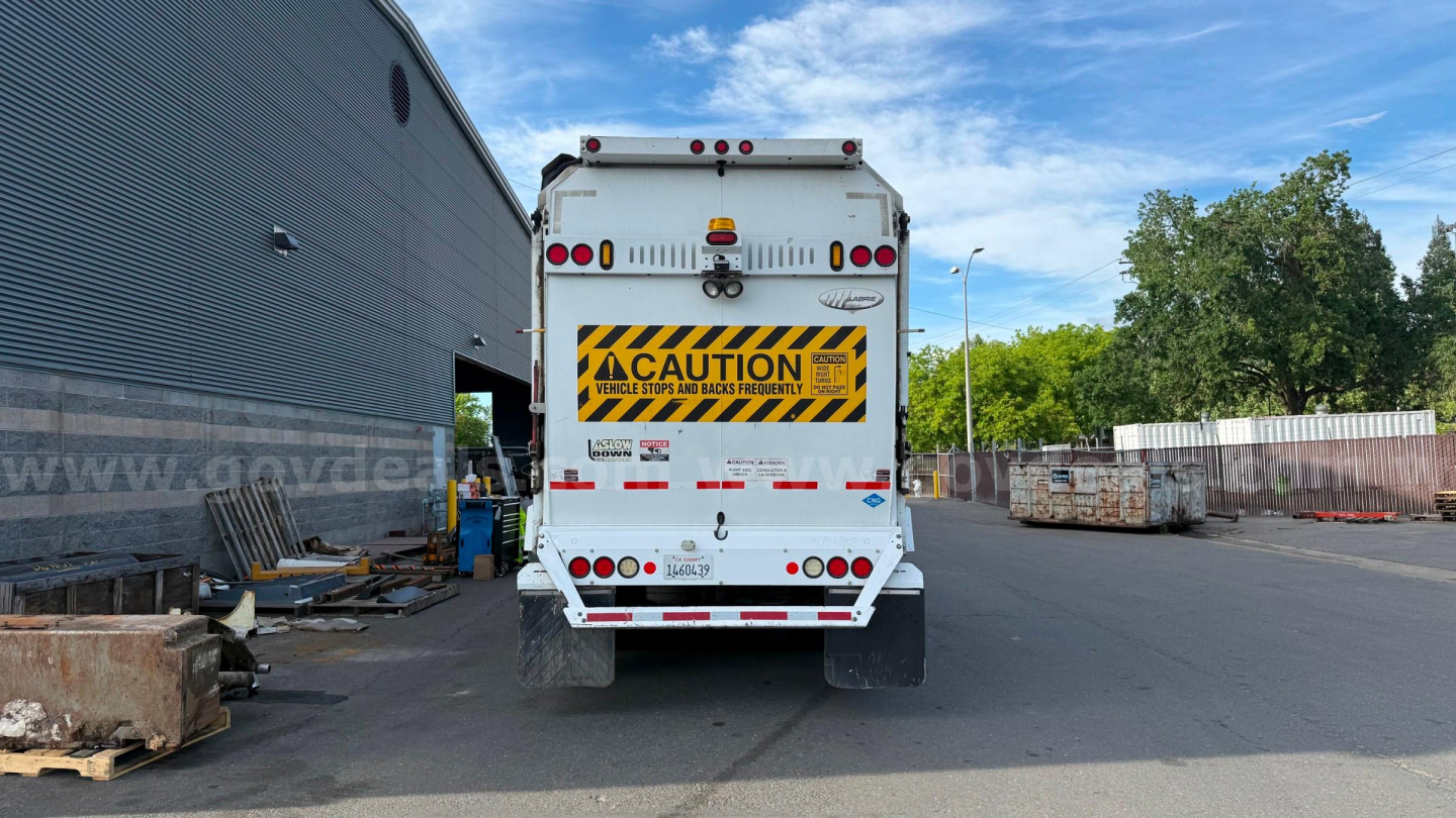 Rear view of 2015 Autocar ACX XPeditor garbage truck showing caution sign and rear lighting.