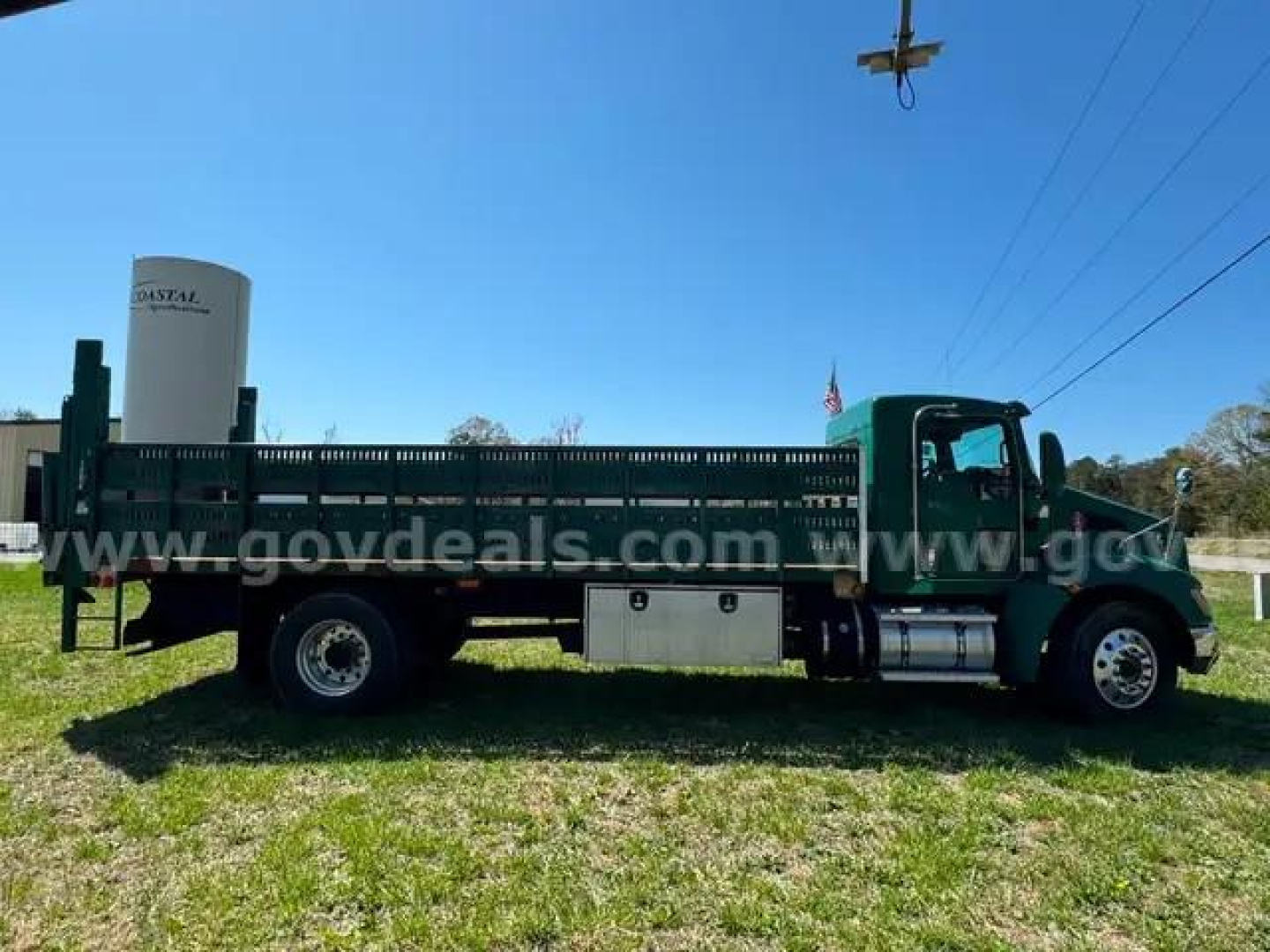 Truck bed and cab of a 2014 Kenworth T370 flatbed truck with aluminum storage boxes and fuel tank.