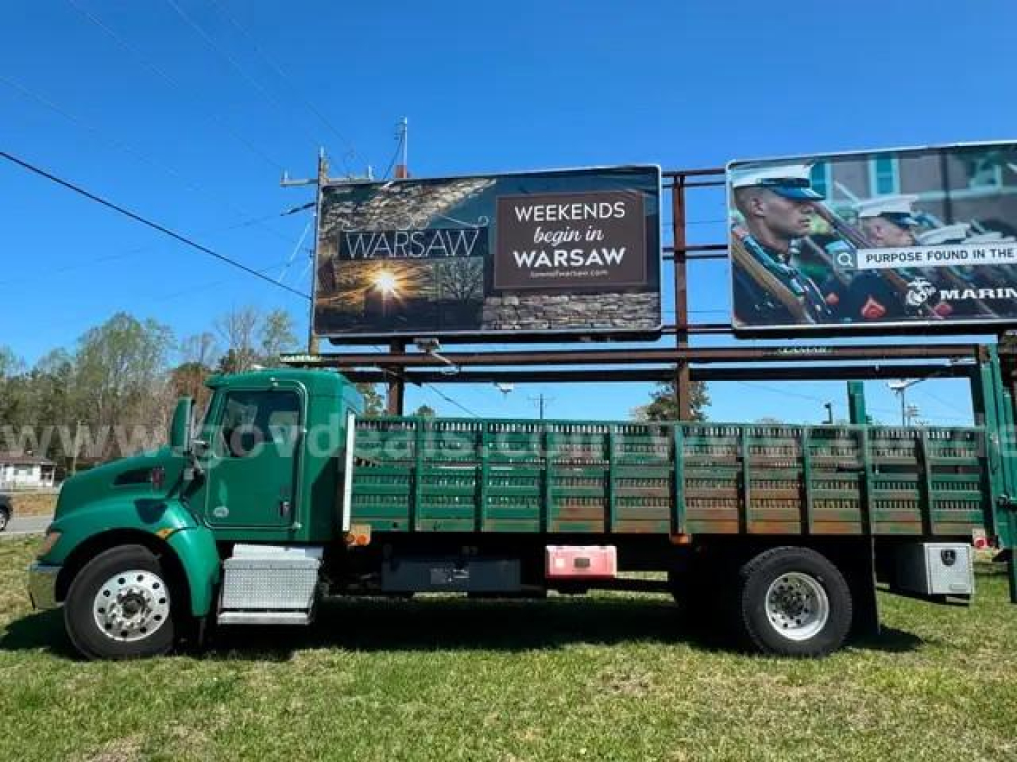 Kenworth T370 flatbed truck side view with green cab and green cargo bed, billboard sign on trailer, no visible text on truck decals.