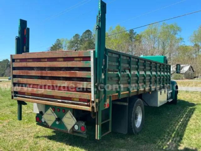 Kenworth T370 flatbed truck rear view showing green stake bed sides and wooden tailgate with reflective triangles