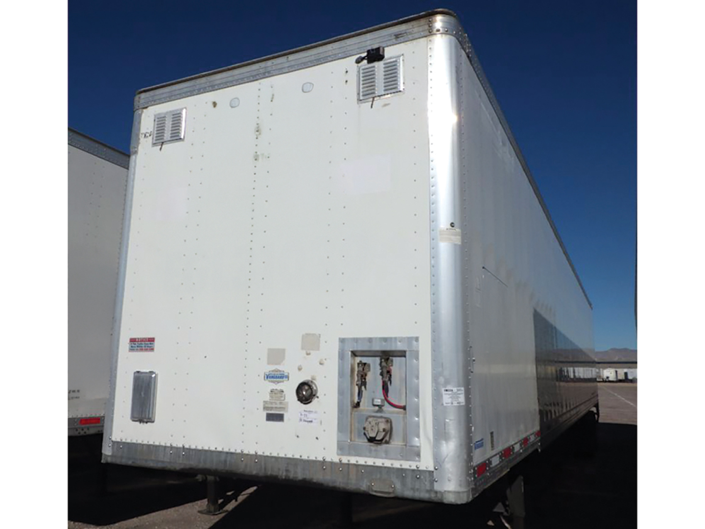 Trailer rear view showing cargo area and service access panel on aluminum Vanguard van trailer, with small vents and reflective markers.
