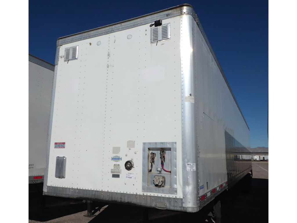 Trailer rear view showing cargo area and service access panel on aluminum Vanguard van trailer, with small vents and reflective markers.