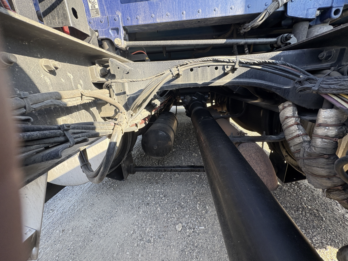 Kenworth truck chassis view showing drive shaft and undercarriage components in the engine bay area.