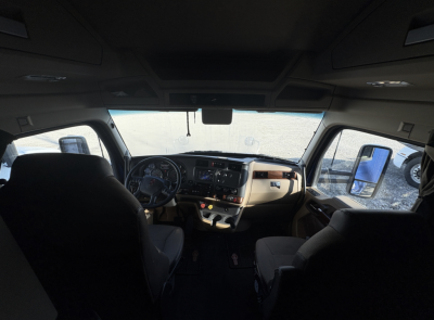 Kenworth T680 cab interior dashboard view facing forward showing steering wheel, center console, and seats.
