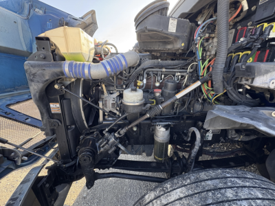Kenworth T680 engine bay view showing various hoses, wiring, and components in the front cluttered with exposed engine parts.