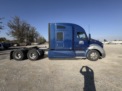 Kenworth T680 side view showing sleeper cab and dual rear axles with ARCO fleet service logo.