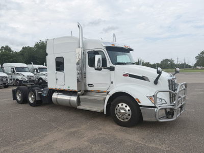 Peterbilt 579 UltraCab tractor in a parking lot showing side view with sleeper cab, chrome bumper guard, and dual rear axles.