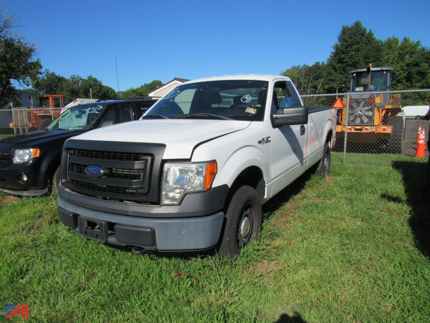 Ford F-150 pickup truck in a grassy lot showing front grille and side view, white cab, 2013 model year.