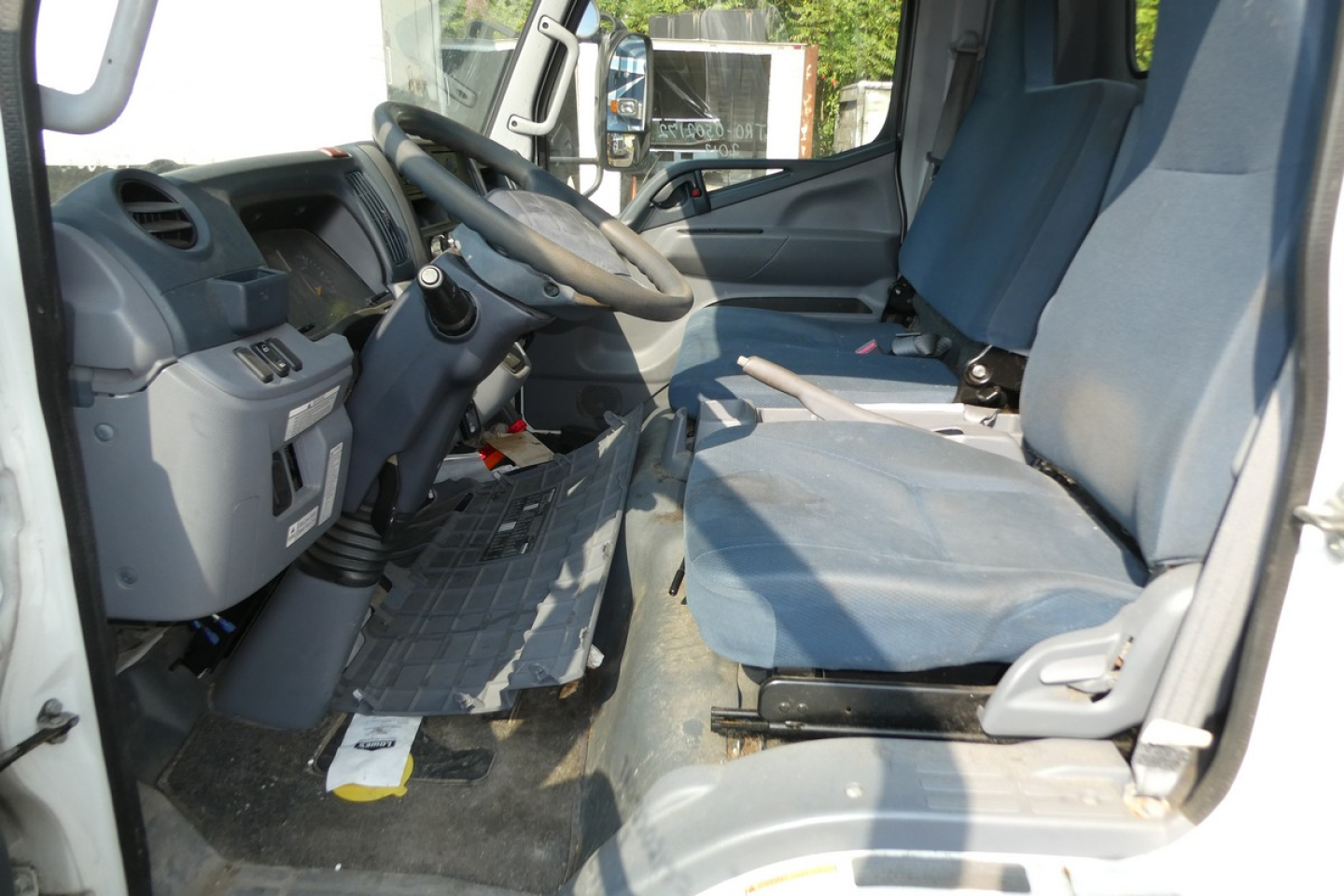 Cab and chassis interior of a 2013 Mitsubishi Fuso FE180 showing steering wheel, driver seat, and front dashboard area.