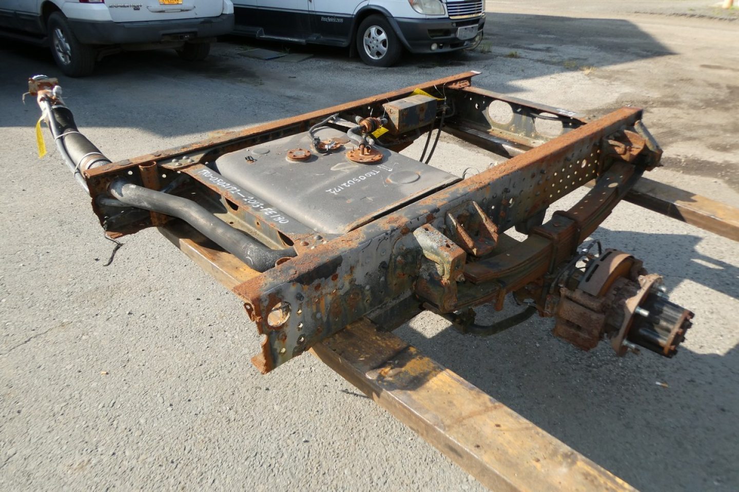 2013 Mitsubishi Fuso FE180 chassis/frame with rusty equipment and differential housing, seen from side on a trailer lot.