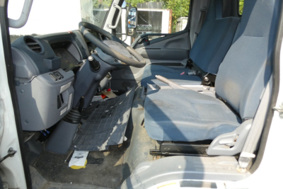 Cab and chassis interior of a 2013 Mitsubishi Fuso FE180 showing steering wheel, driver seat, and front dashboard area.