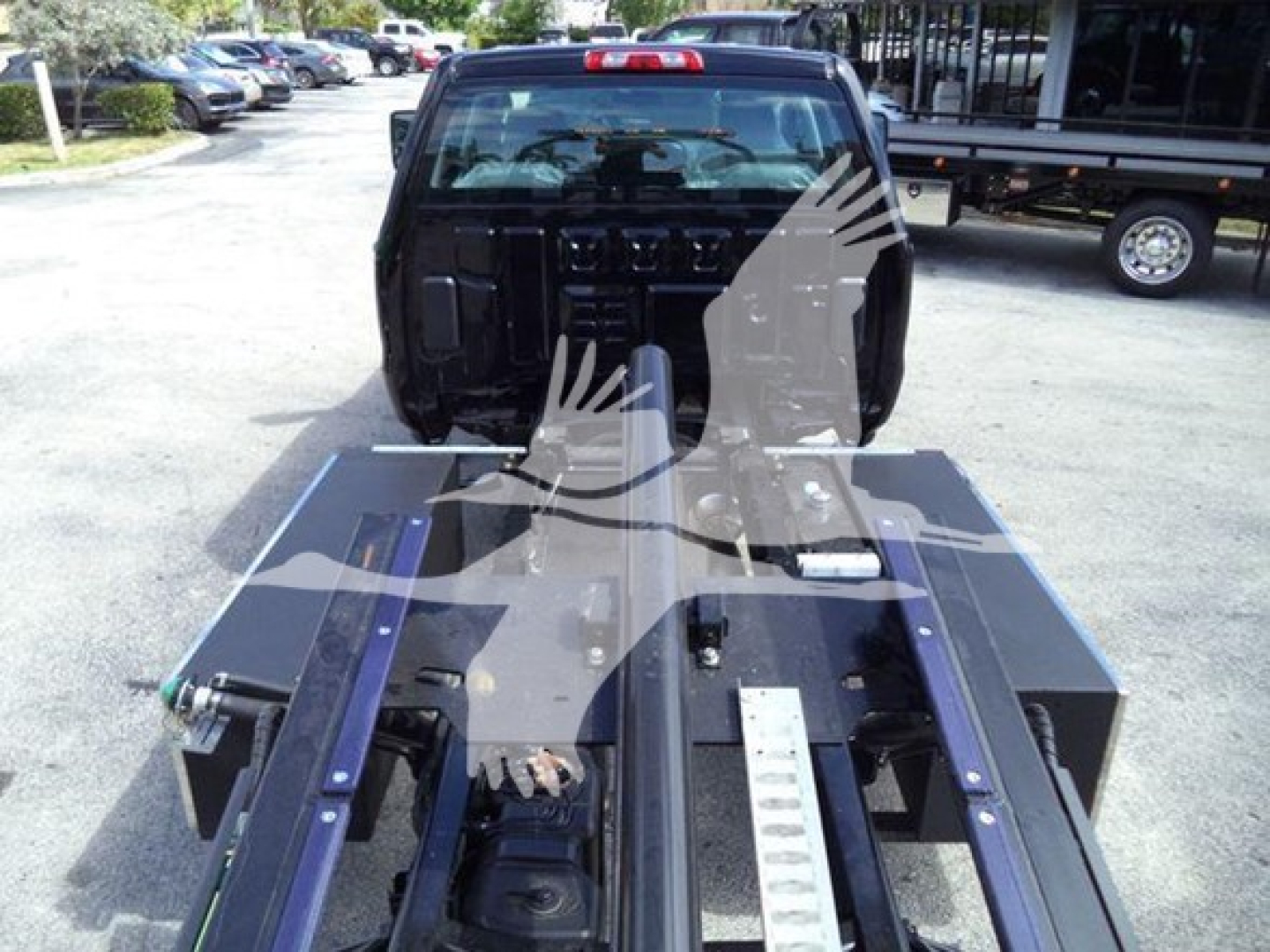 Truck cab and rollback bed from rear with metal platform and rails; blurred watermark overlay. Visible text includes VIN 1HTKTSWK9PH419807 on the listing context (not on the image).