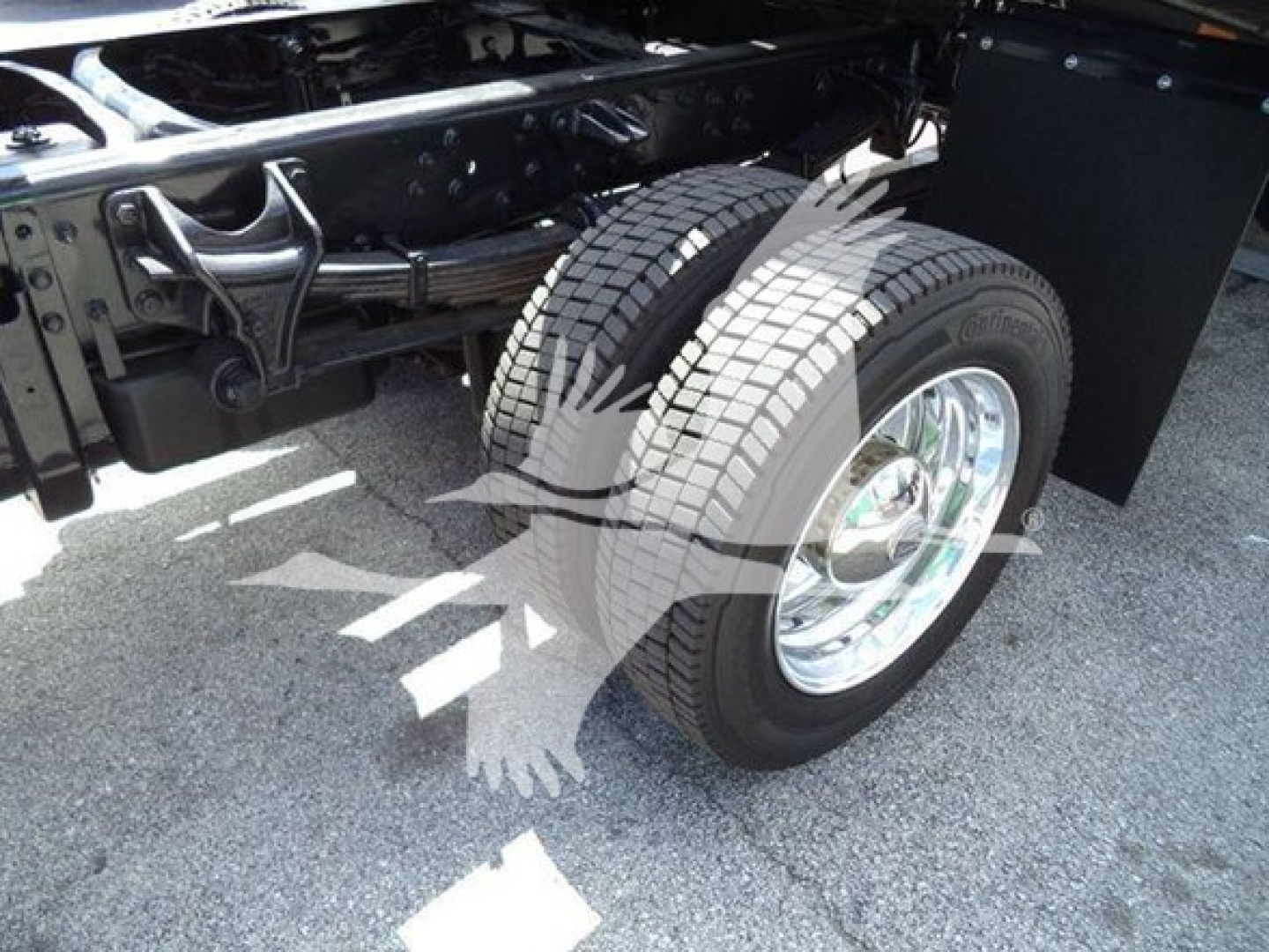 Dual rear wheels and wheel well of a truck chassis showing chrome rims and dual tires in a rollback truck setup.