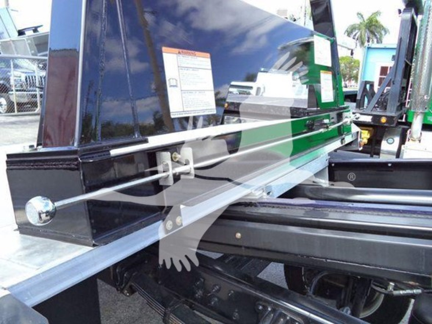 Truck rollback equipment with hydraulic rails and reflective metal beams showing label stickers and frame components.