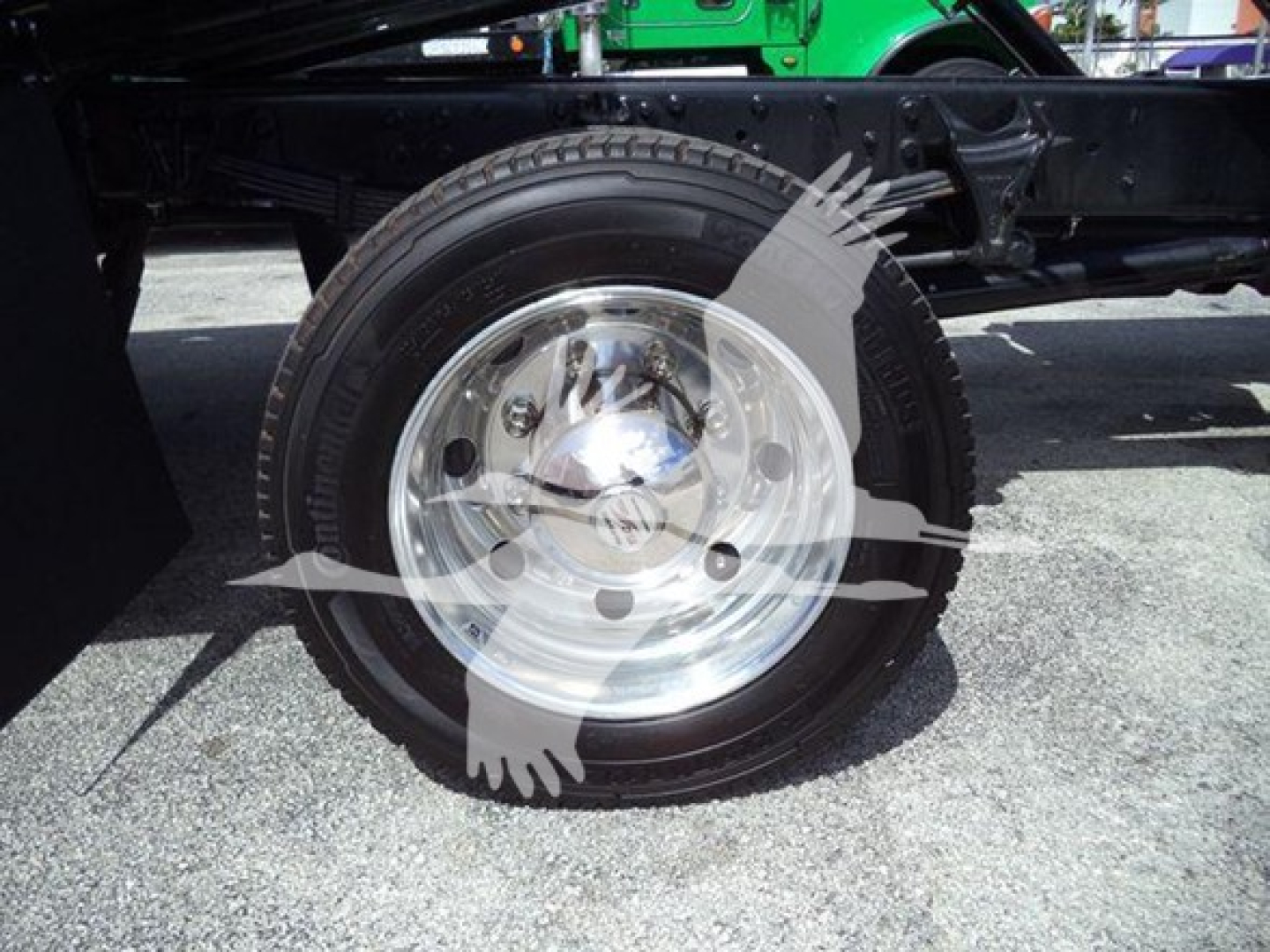Truck wheel and tire close-up on a 2023 International CV rollback truck, chrome hubcap and black tire visible.