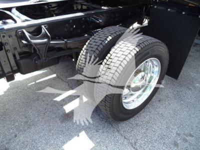 Dual rear wheels and wheel well of a truck chassis showing chrome rims and dual tires in a rollback truck setup.