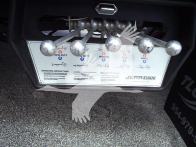 Truck control panel with multiple metal levers and wiring, showing labels and diagrams for operating the rollback winch and jug features on a Jerr-Dan system.