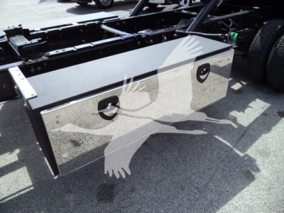 Toolbox/storage box mounted on a truck chassis with metal finish and two circular locks, adjacent to wheel area.