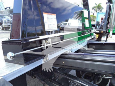 Truck rollback equipment with hydraulic rails and reflective metal beams showing label stickers and frame components.